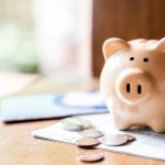 Piggy bank with coins and saving book bank on wooden table