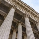Vintage Old Justice Courthouse Column. Stone column ancient classic architecture detail. Abstract view of neoclassical fluted columns bases and steps of Court building